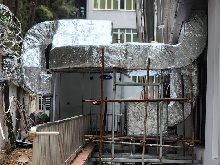 Technician installing insulated ductwork on scaffolding